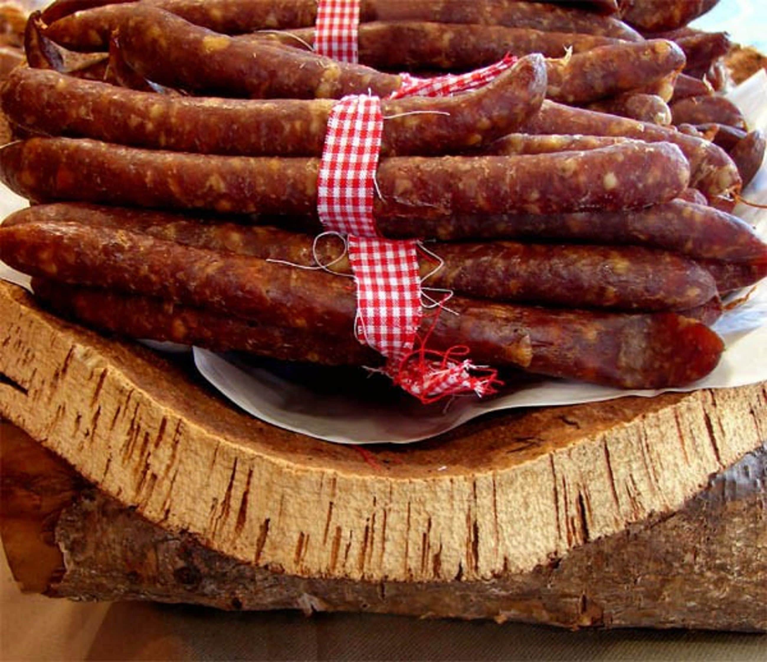 A stack of sausages tied with a red and white checkered ribbon.