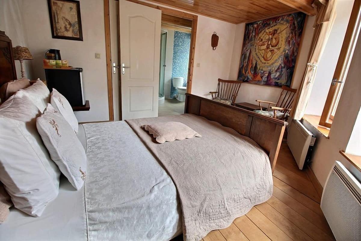 A bedroom with a large bed, a small desk, a chair, and a window.