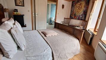 A bedroom with a large bed, a small desk, a chair, and a window.