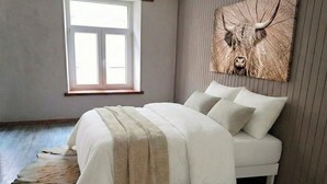Un dormitorio con una cama, una ventana y una obra de arte en la pared que representa a un toro.