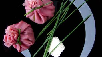 Un plato negro con tres rosas rosadas y varias cebollitas verdes.