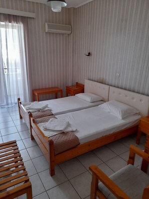 A hotel room with two single beds, a wooden nightstand, a small table, and a chair.