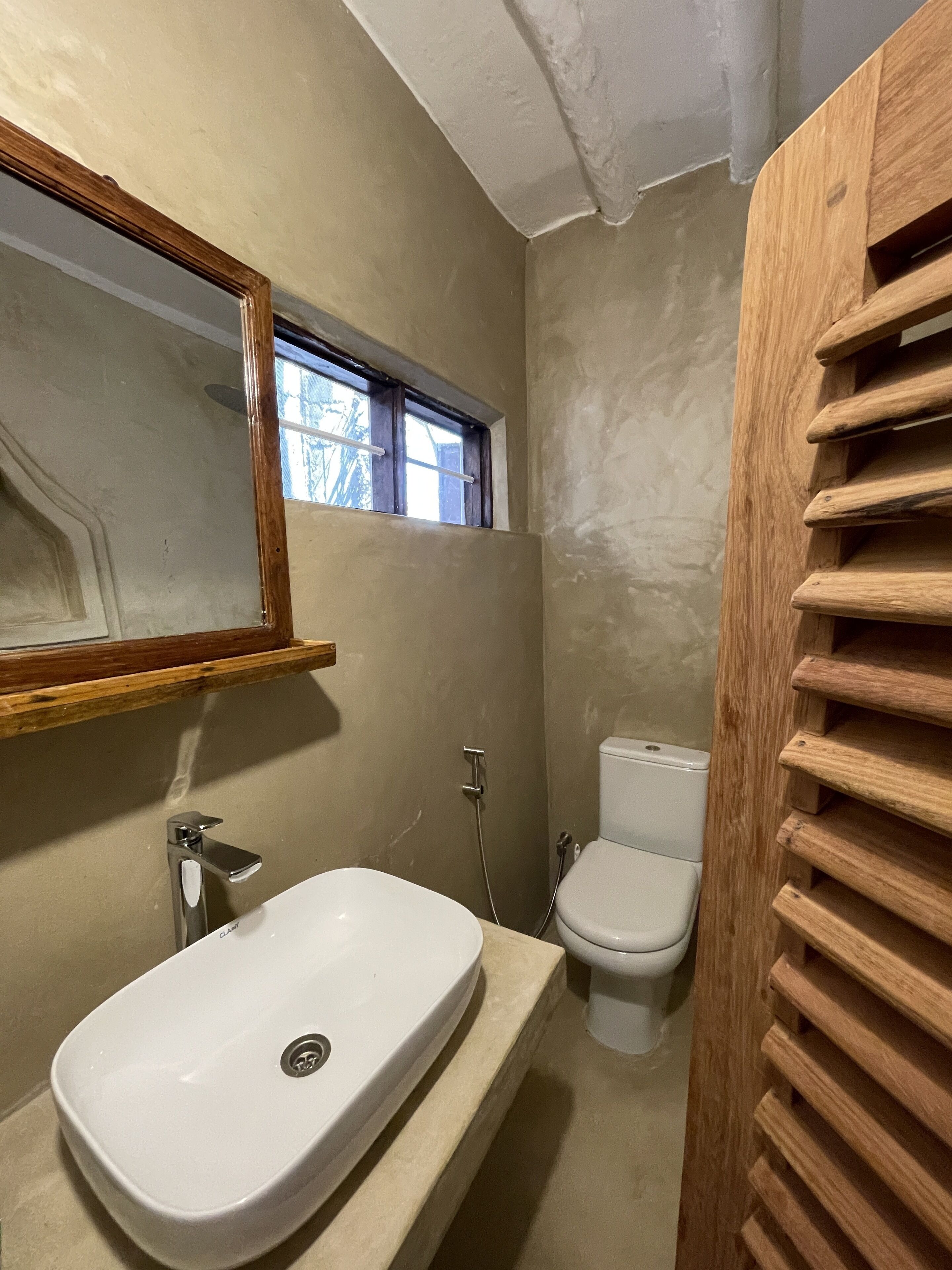 Ein Badezimmer mit einem weißen Waschbecken, einer Toilette und einem Fenster.