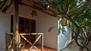 Une structure en bois comprenant une table et des chaises, une fenêtre et un arbre dans une cour.