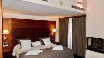 Una habitación de hotel con una cama grande, dos lámparas de noche, una chimenea y un cabecero de madera.