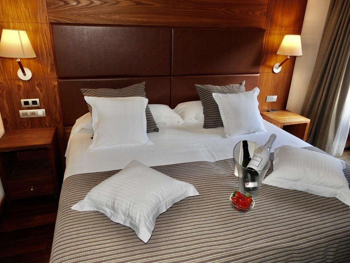 A hotel room with a large bed, two bedside tables, and a headboard.