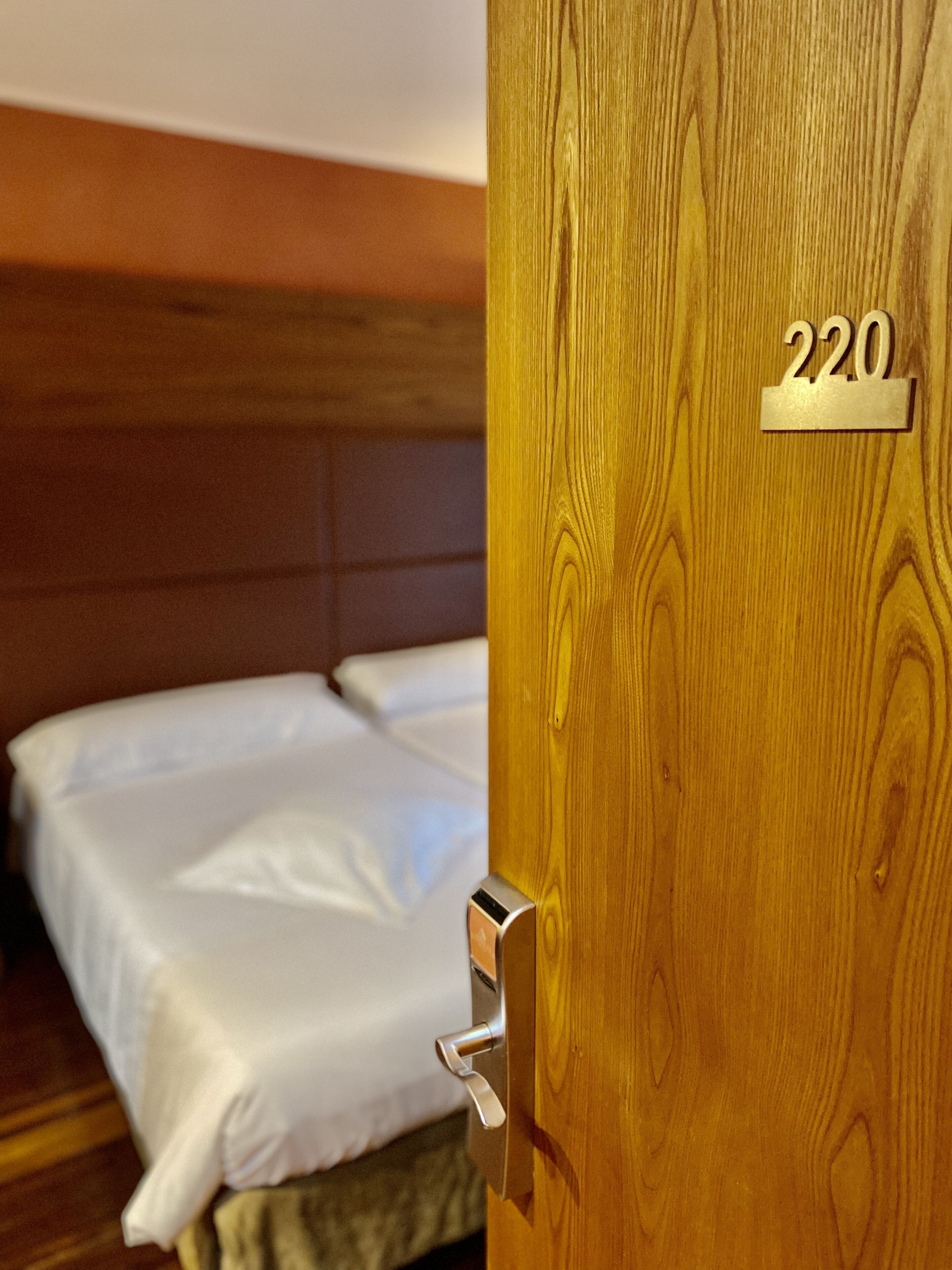 Una puerta de madera con un picaporte de metal y una placa con el número de habitación.