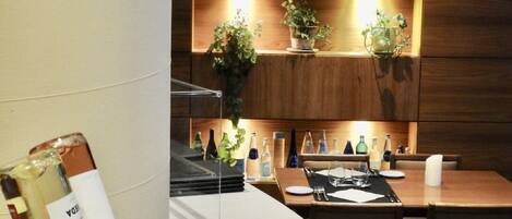 A modern kitchen with wooden cabinets, a white countertop, and a dining area with a table set for two.