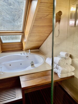 A modern bathroom with a freestanding bathtub, a glass shower enclosure, and a stack of white towels.