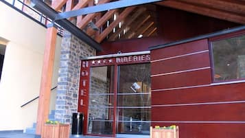 A hotel entrance with a stone facade and a red awning.