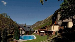 Eine Berghütte mit Schwimmbad, Sitzgelegenheiten im Freien und Blick auf die Berge.