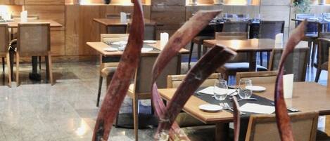 Een modern restaurantinterieur met houten lambrisering, tafels en stoelen voor het diner.