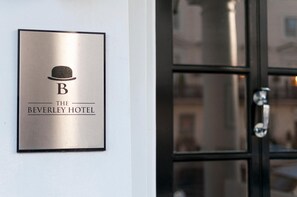 A hotel sign with a hat symbol and the name "The Beverley Hotel". - The Beverley Hotel (London)