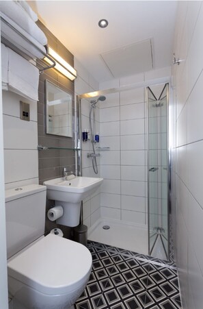 Une salle de bain moderne équipée de toilettes, d’un lavabo et d’une douche à parois de verre.