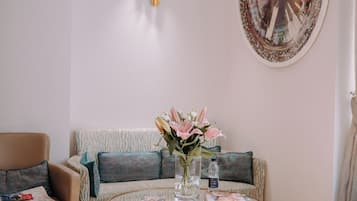 Una habitación con una mesa de centro redonda, un sofá, una silla y una lámpara fijada a la pared.