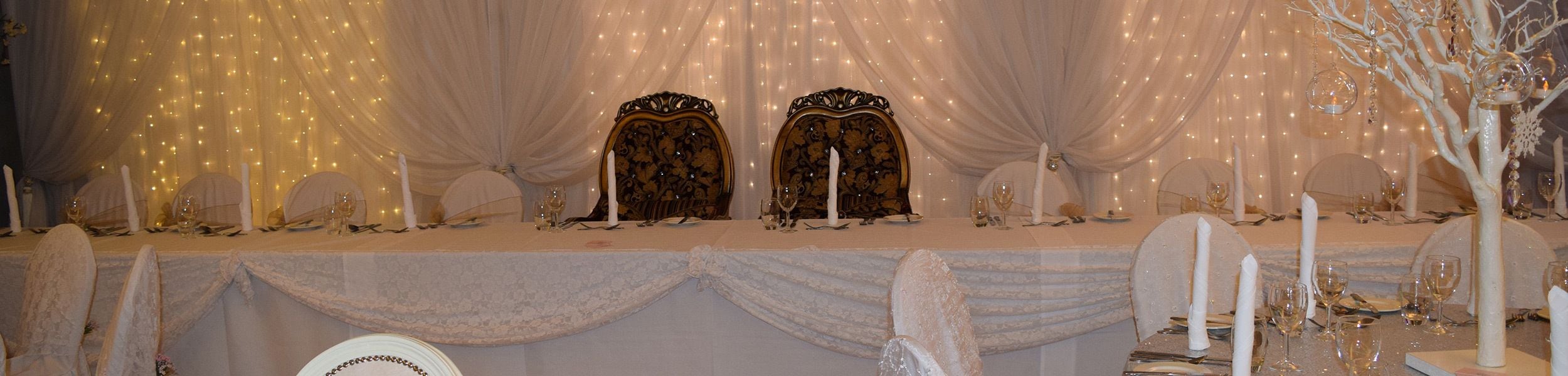 Une table de banquet dressée avec des nappes blanches, des chaises élégantes et des chandeliers.