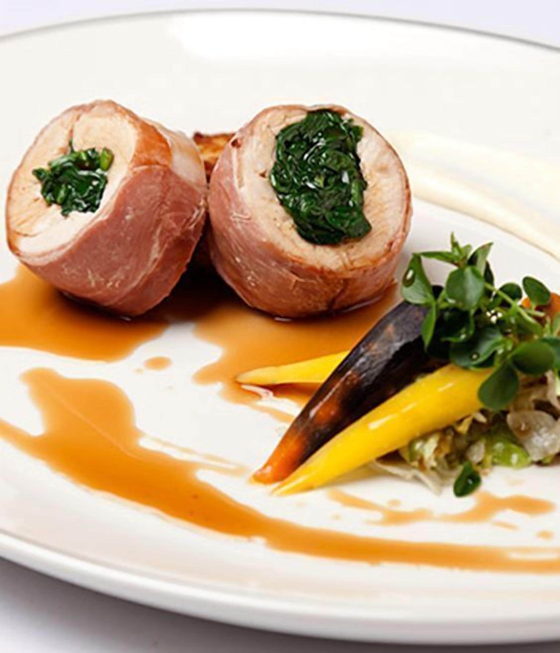 A plate with a stuffed meat dish, a sauce, and some vegetables.