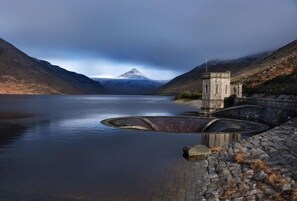 A serene lake with a mountain in the background, a stone structure, and a clear sky. - Kilmorey Arms Hotel (Newry)