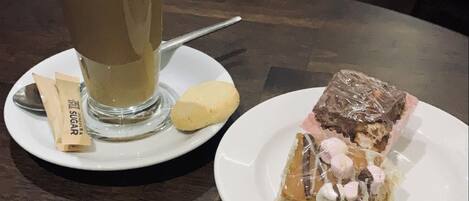 Una mesa con un vaso de café helado y una porción de pastel sobre platos.