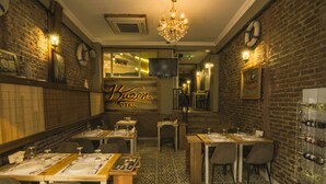 Un restaurant aux murs de briques, agrémenté d’un lustre et d’un présentoir à bouteilles de vin.