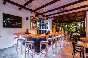 A bar area with a wooden ceiling, a wine rack, and a bar counter with stools.