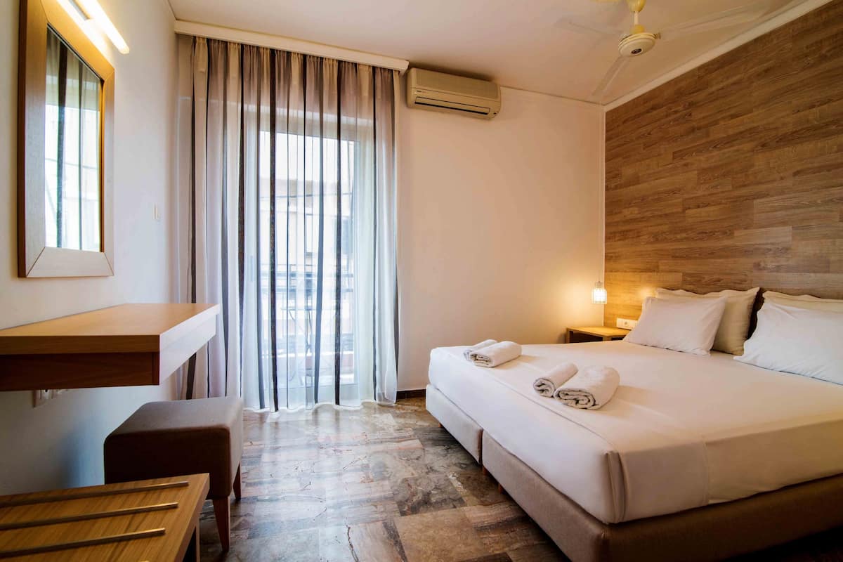 Una habitación de hotel con cama, mesita de noche y escritorio con silla.
