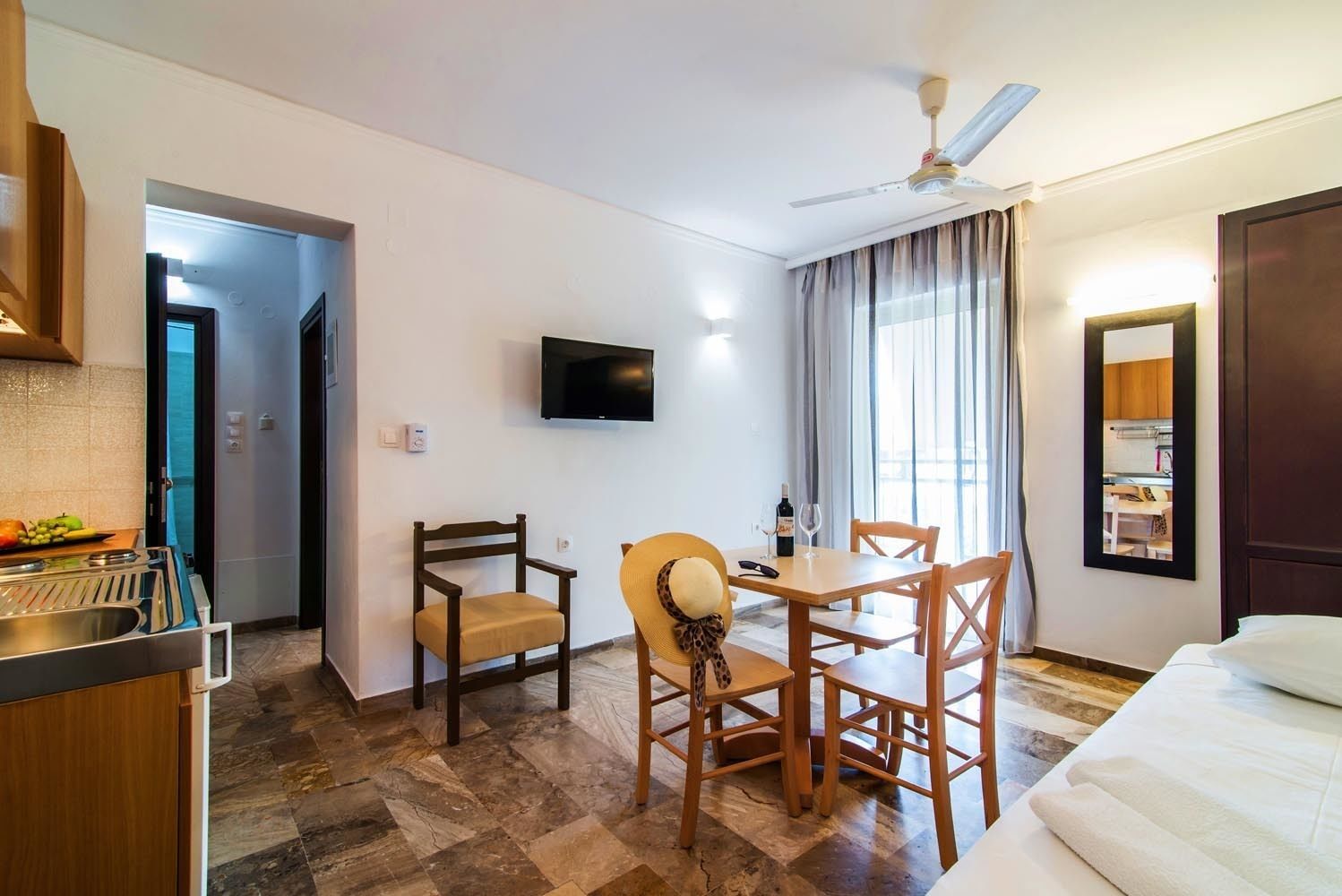 Une chambre d’hôtel comprenant un coin repas, une télévision, un ventilateur de plafond et un lit.