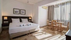 Une chambre d’hôtel avec un lit, un bureau et une chaise. Deux tableaux encadrés sont accrochés au mur.