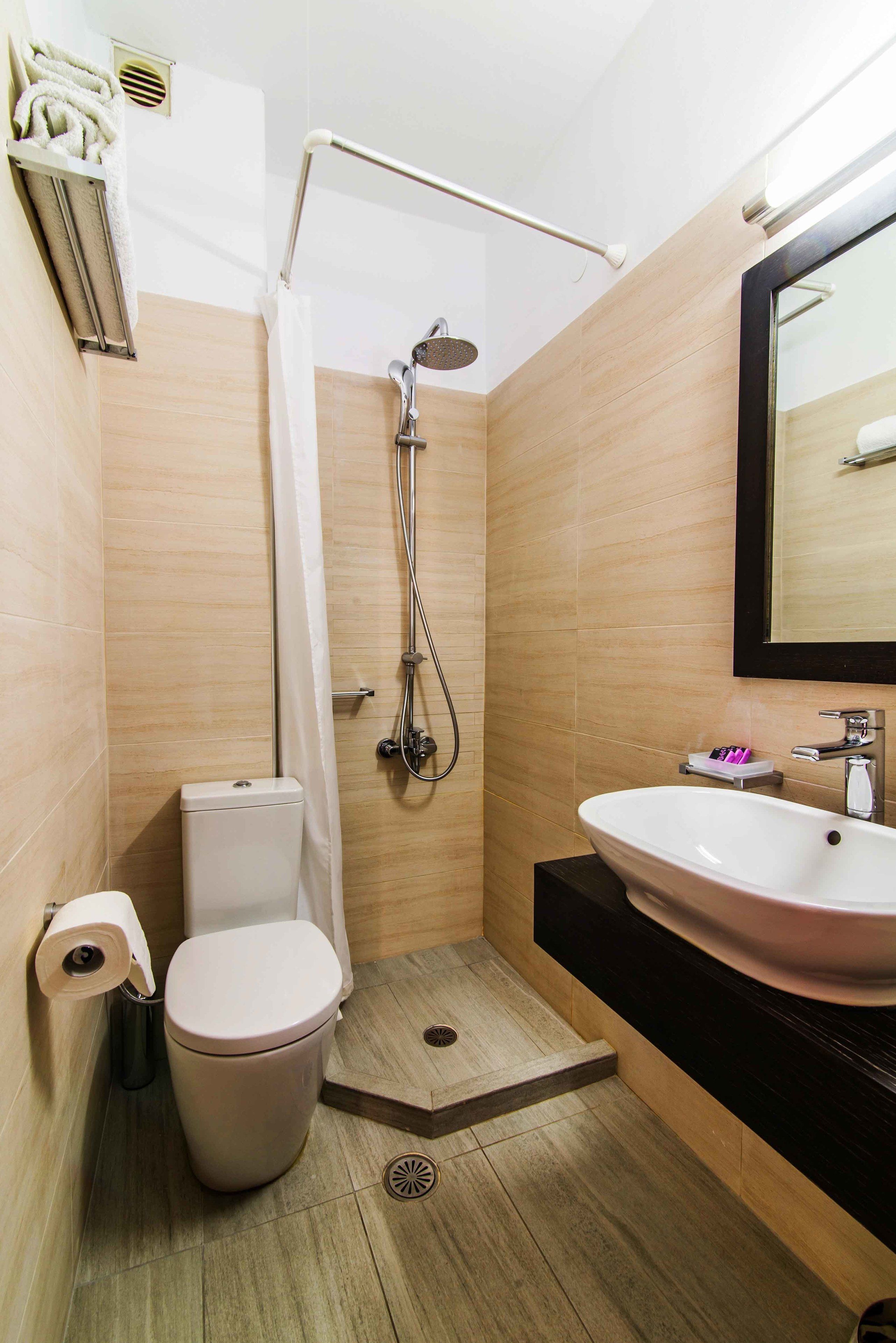 A modern bathroom with a shower, toilet, and sink.
