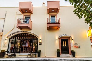 A building with a bar on the ground floor, a balcony on the second floor, and a sign for a hotel.