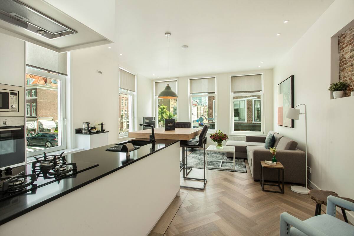 Een moderne keuken met een centraal eiland, een zithoek met een bank en uitzicht op de straat.