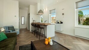 Un salon moderne avec un canapé, une table basse et un coin cuisine comprenant un bar et des tabourets.