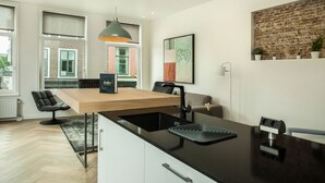 Une cuisine moderne avec un plan de travail noir, un évier encastré et un luminaire suspendu.