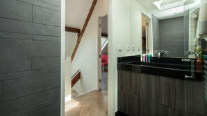 Une salle de bain moderne avec un plan de toilette noir, une douche en verre et un escalier en bois.