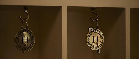 Two keychains with the emblem of the Helene Kilde hotel from 1904.