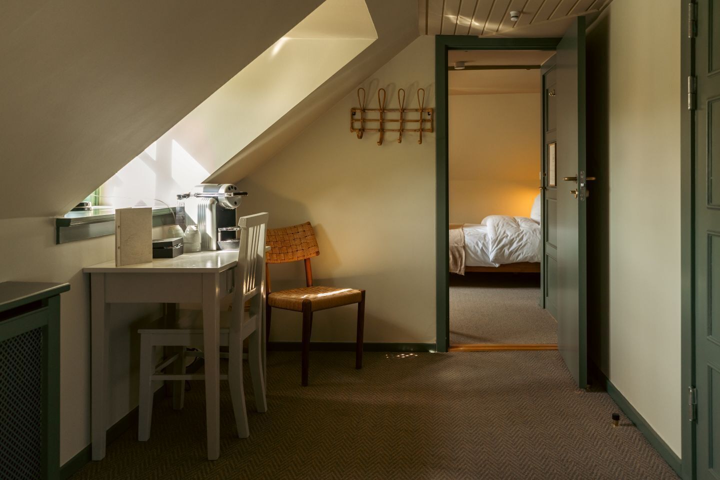 Une pièce de taille modeste, avec un bureau, une chaise et un lit à l’arrière-plan.