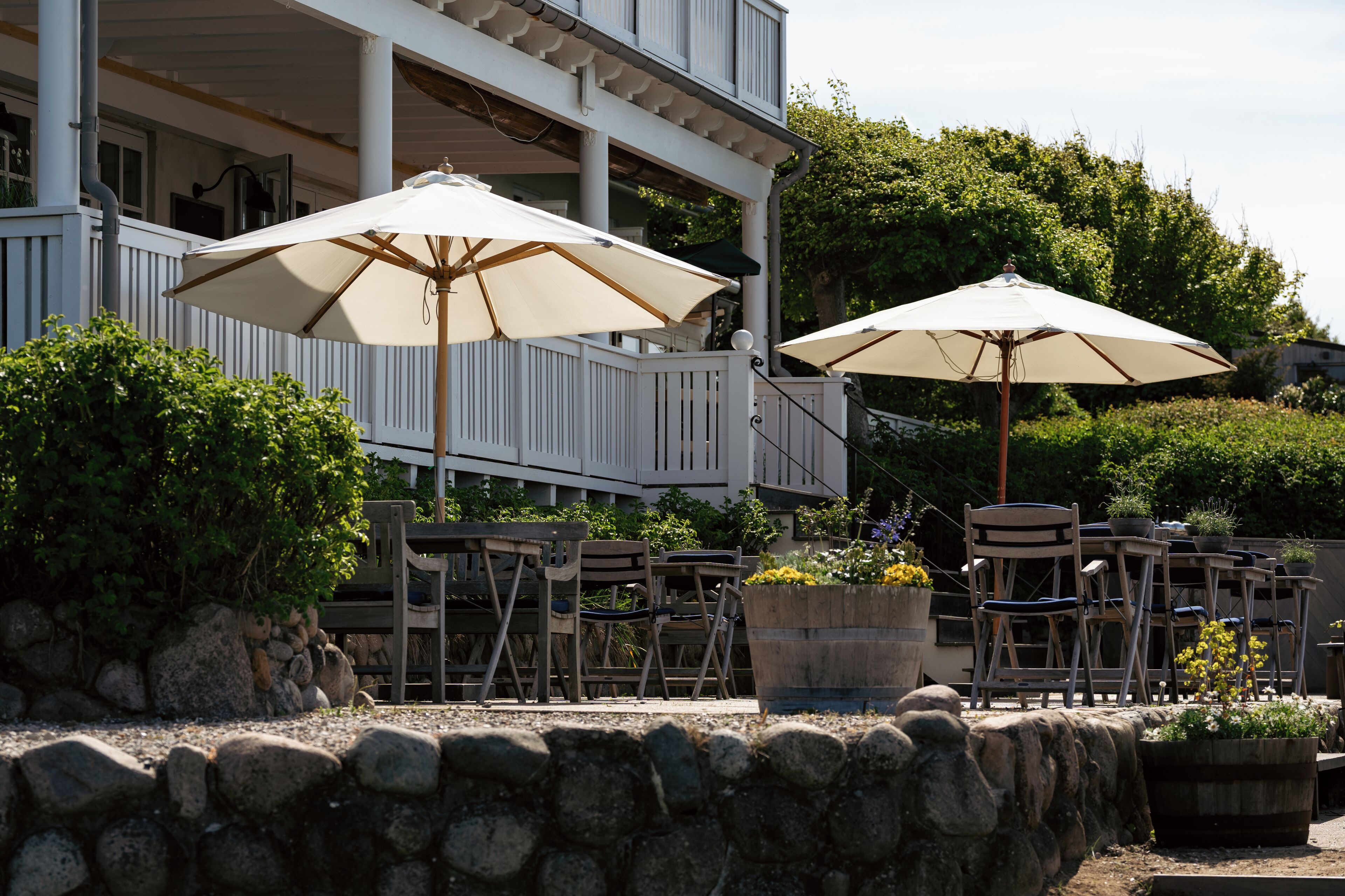 A patio with outdoor seating, including tables and chairs, and two large umbrellas providing shade.
