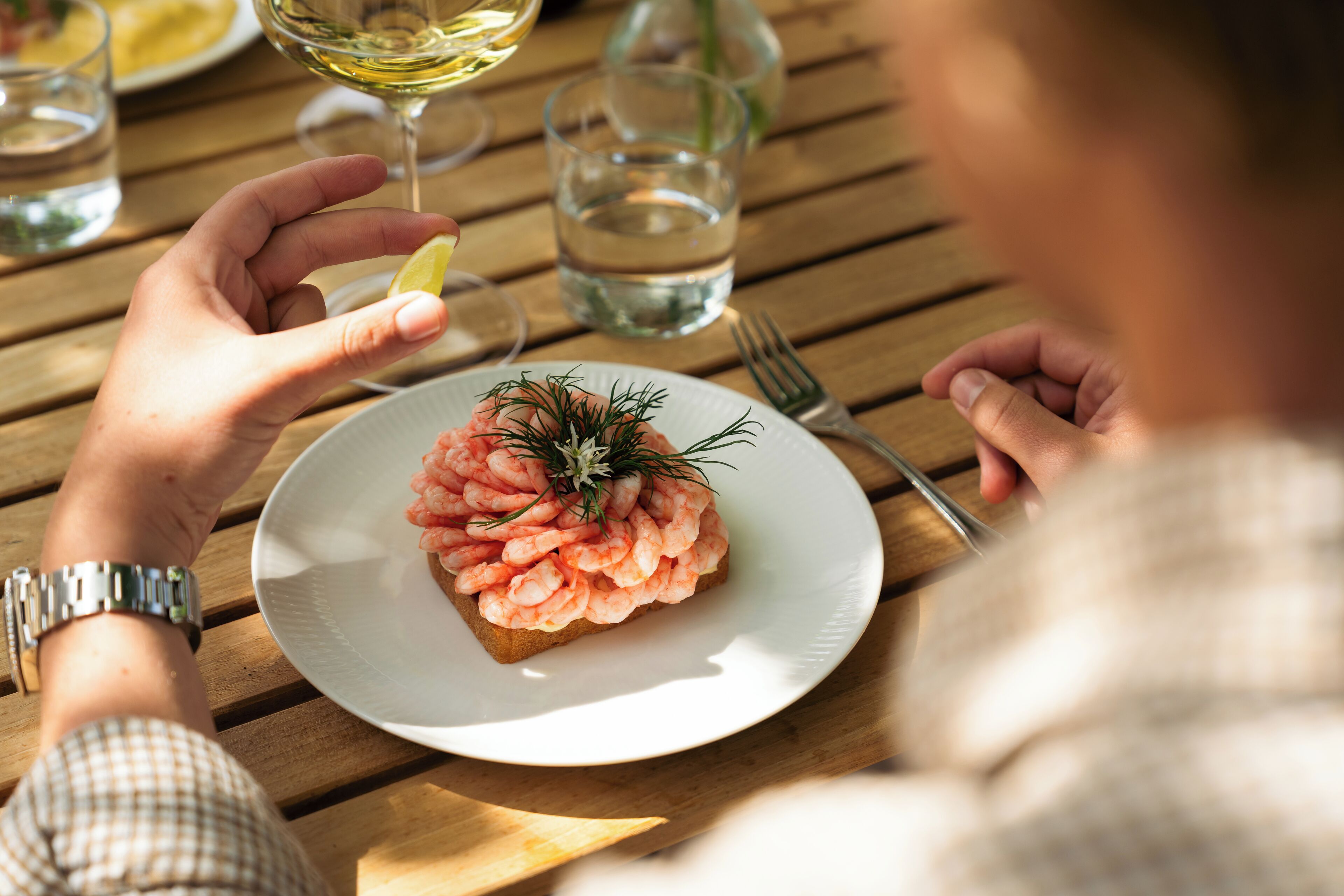 Ein Holztisch mit einem Teller Essen, einem Glas Wasser und einer Gabel.