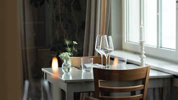 Una mesa de comedor con sillas, una vela y una ventana con cortinas.
