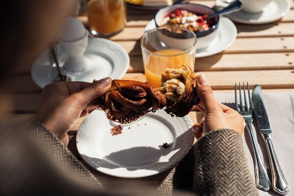 A breakfast setting with a plate of food, a glass of orange juice, and a fork and knife on a wooden table. - Helenekilde Badehotel (Tisvildeleje)