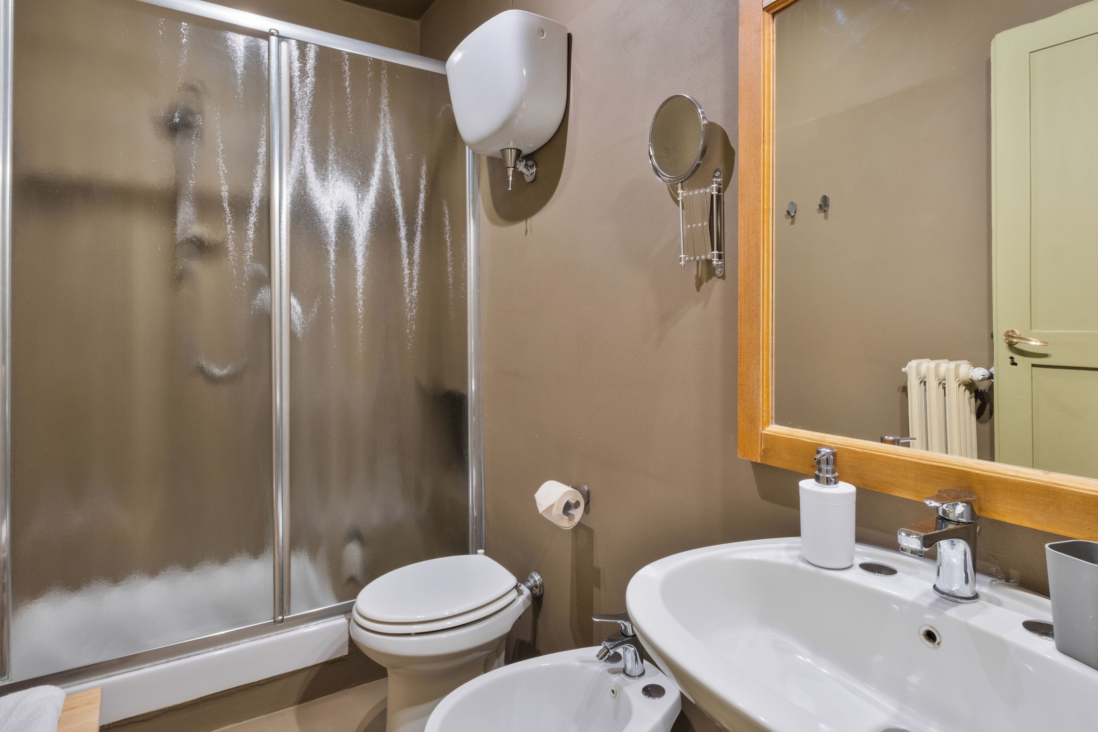 Baño con inodoro, lavabo, espejo y ducha.