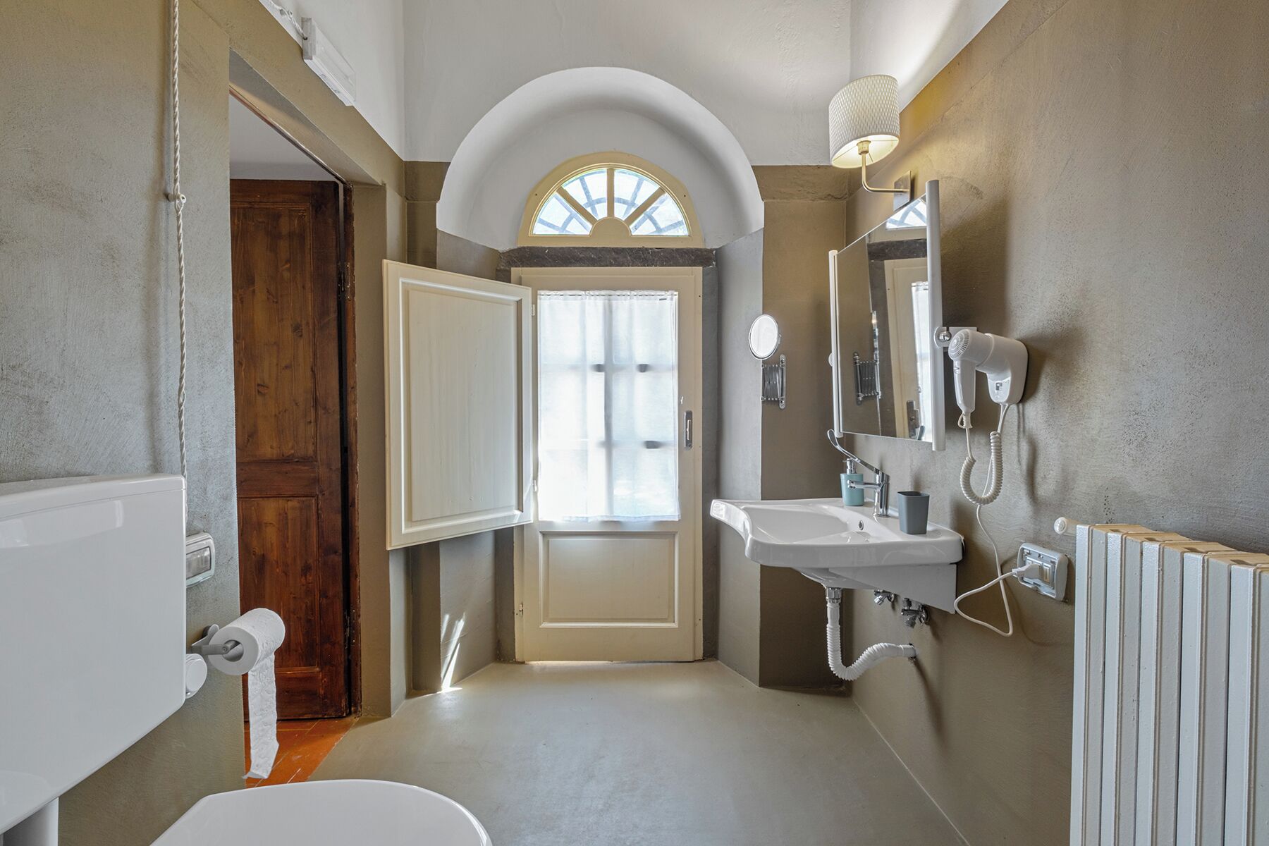A bathroom with a toilet, sink, hairdryer, and a mirror.