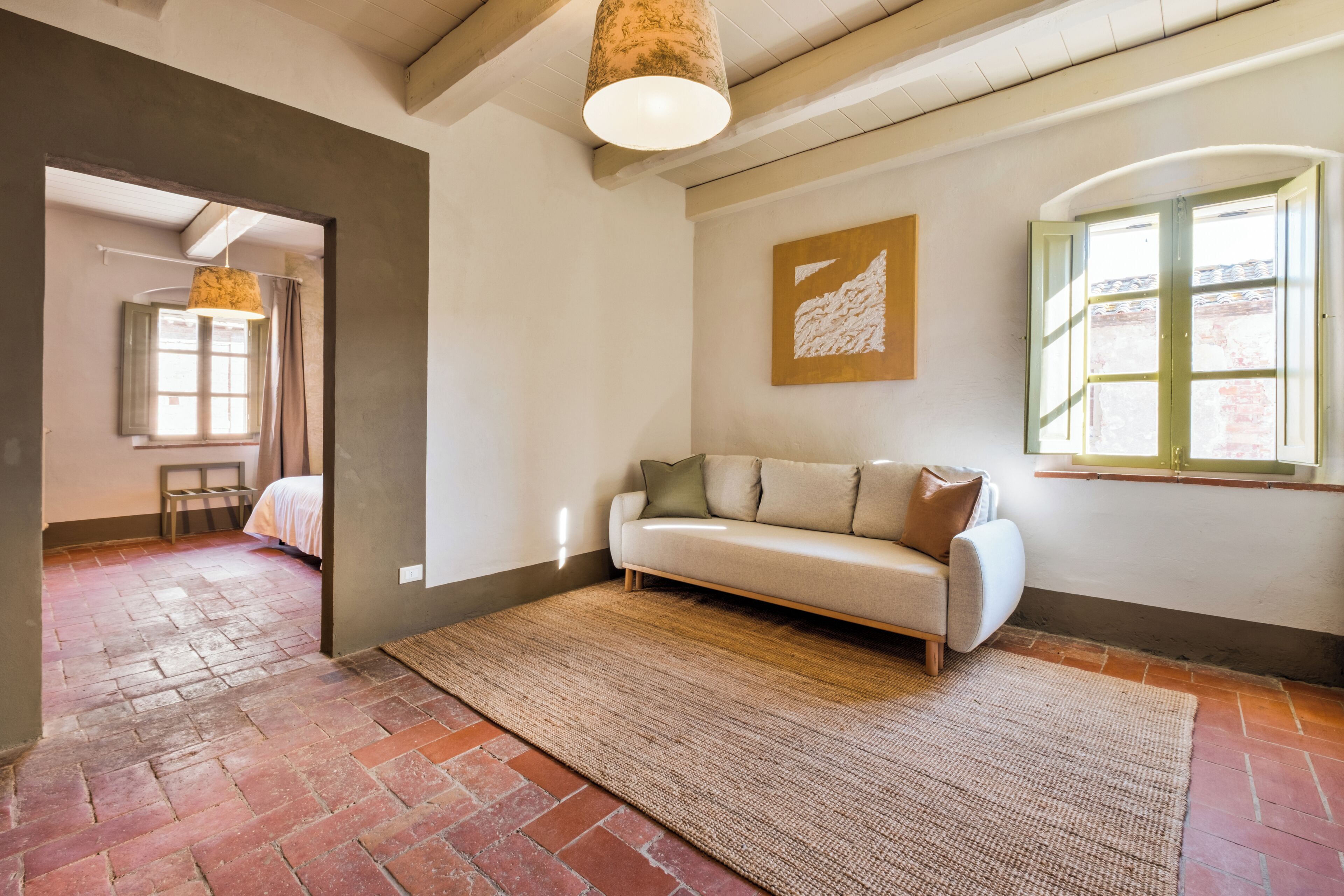 Una habitación con sofá, alfombra, ventana con vistas y lámpara colgante.