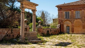 An ancient stone structure with columns and a building with arched windows. - Tenuta la Fratta (Sinalunga)