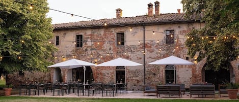 A rustic building with outdoor seating and string lights.