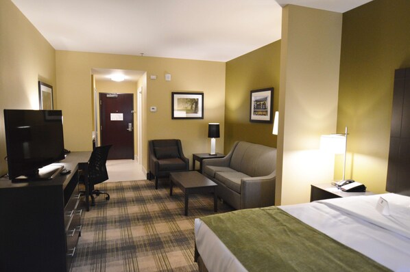 Une chambre d’hôtel équipée d’un lit, d’un bureau avec un ordinateur, d’une chaise, d’un canapé et d’une télévision.