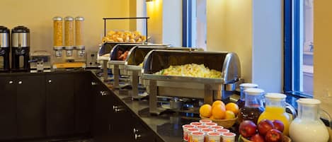 A buffet with various food items and beverages, including cereal, fruits, and juices.