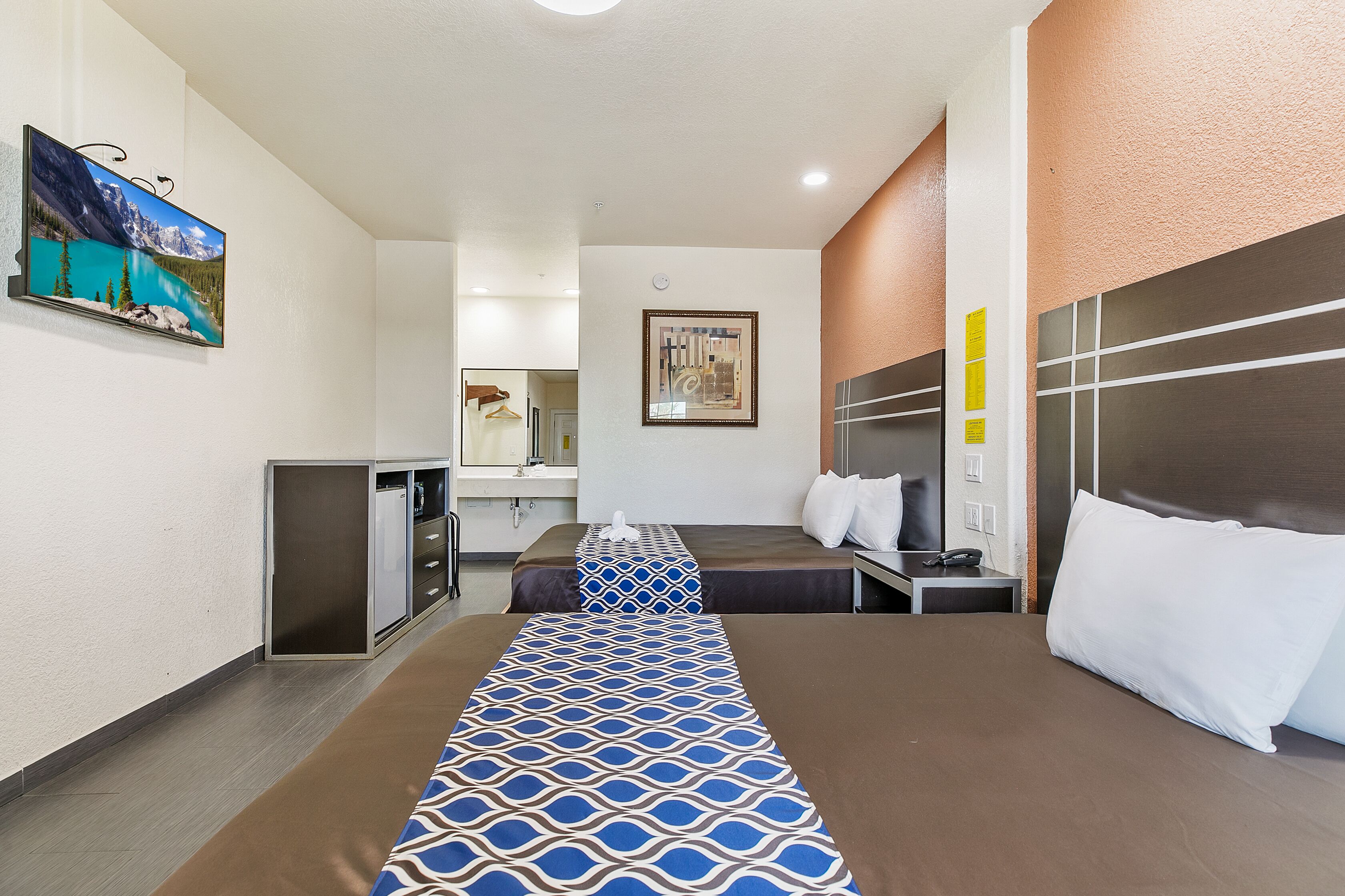 A hotel room with a bed, bedside table, and a small desk.