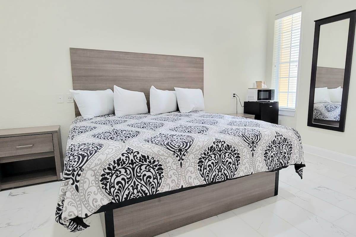 A bedroom with a bed, bedside tables, a mirror, and a window with blinds.