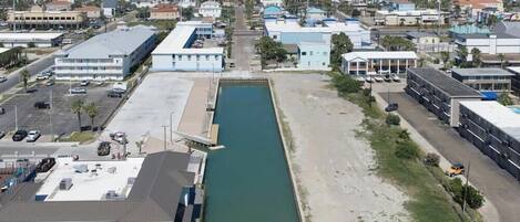 A coastal urban area with a narrow waterway, buildings, and a parking lot.